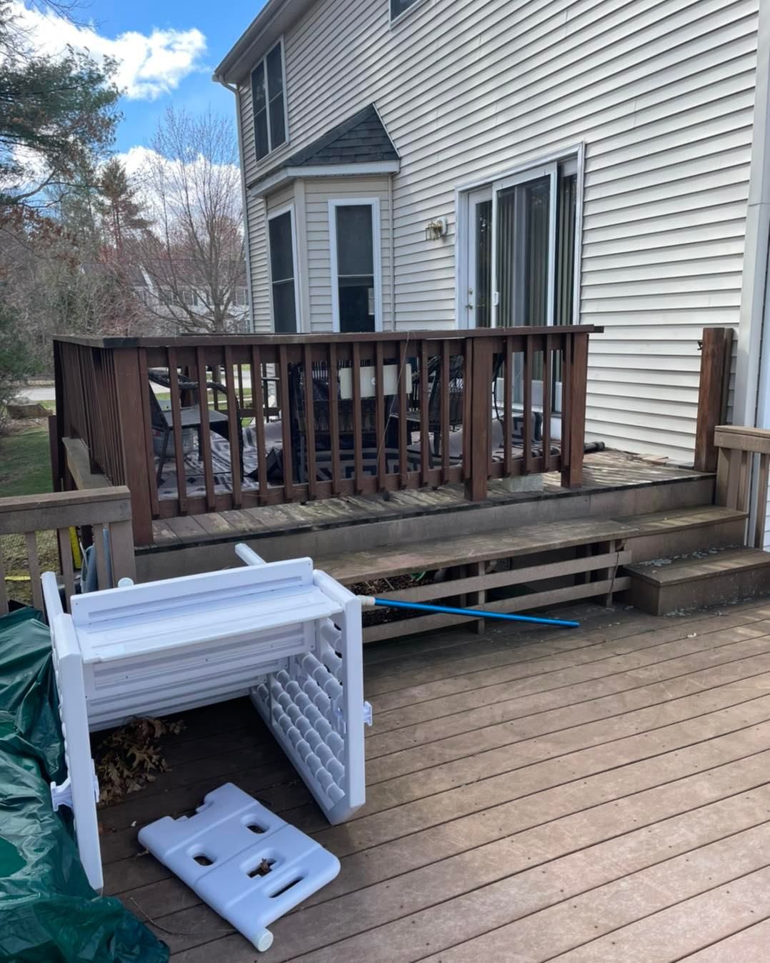 A white table is sitting on a wooden deck next to a house