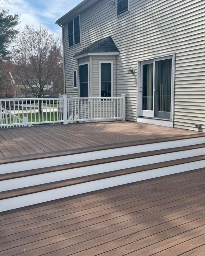 A wooden deck with stairs and a white railing in front of a house