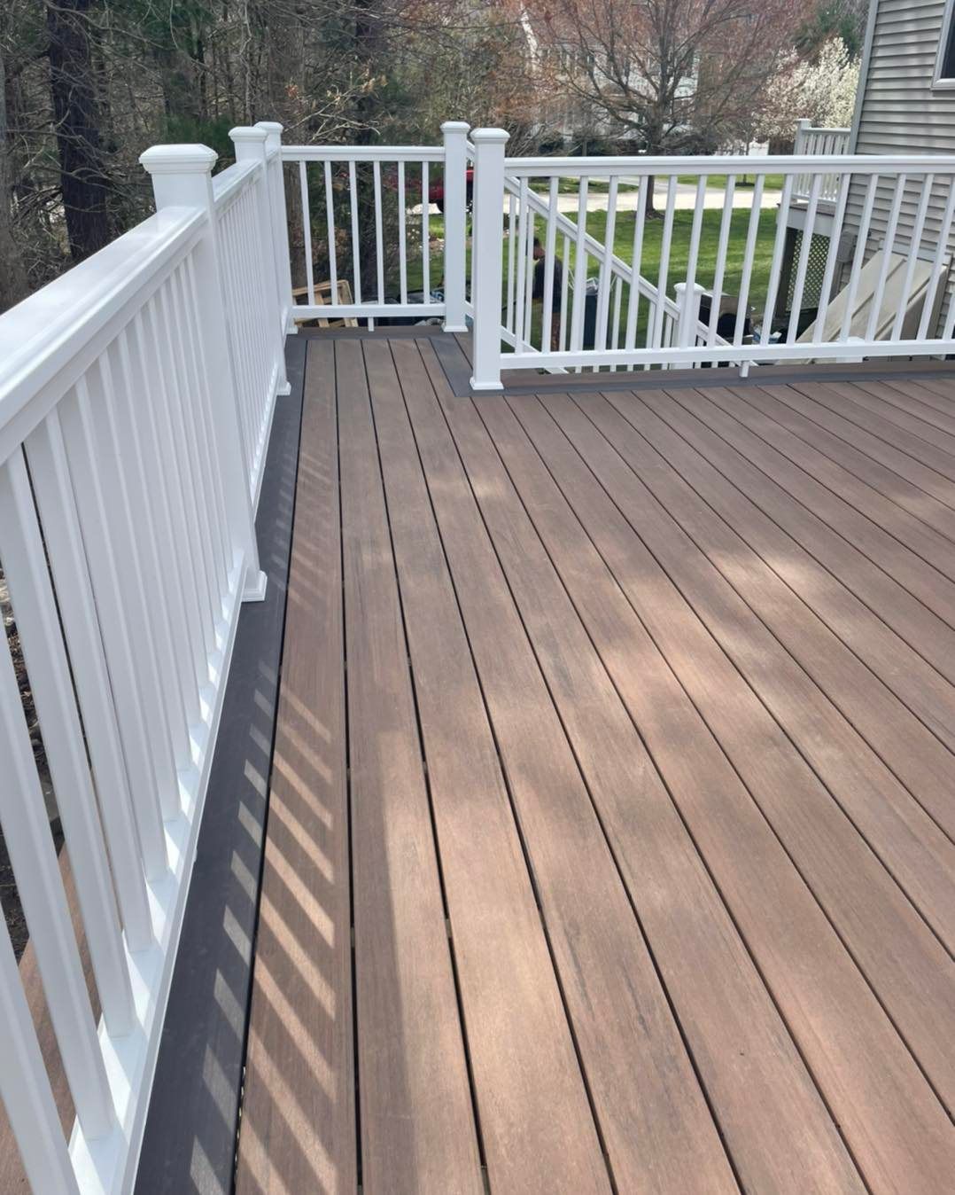 A wooden deck with a white railing and stairs