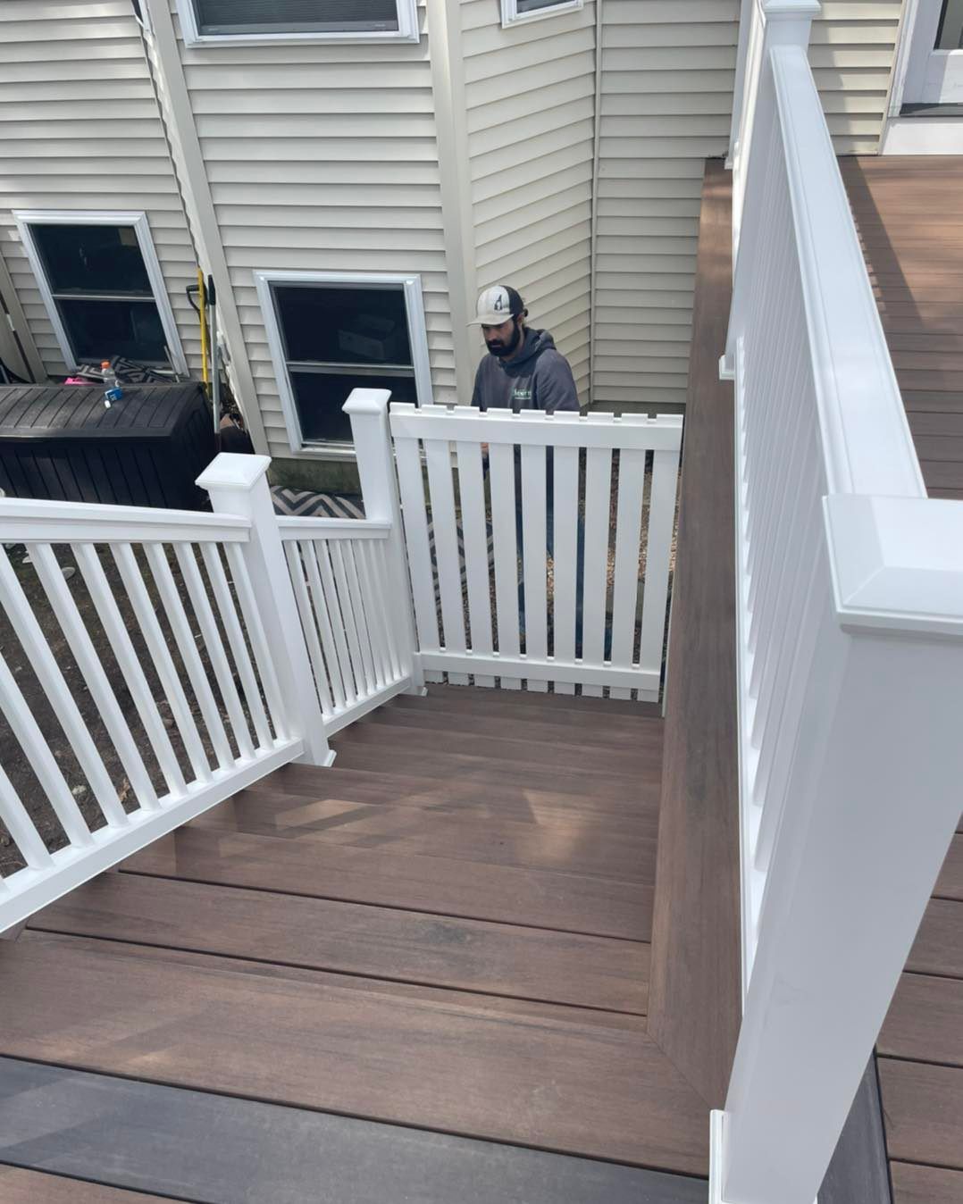 A man is standing on a deck with a white railing
