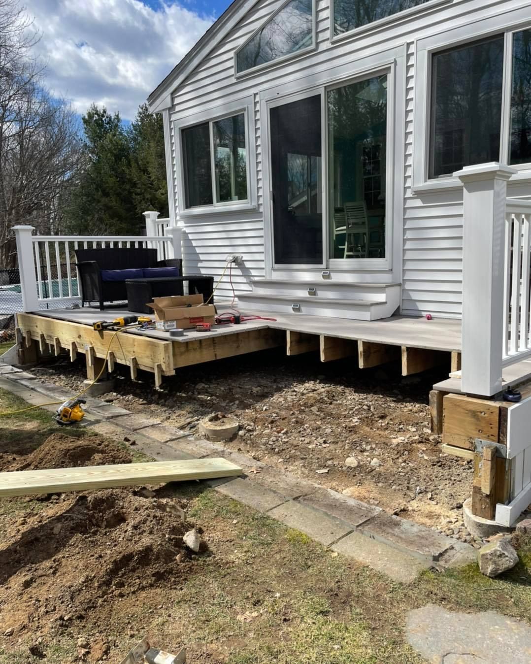 A white house with a wooden deck being built in front of it