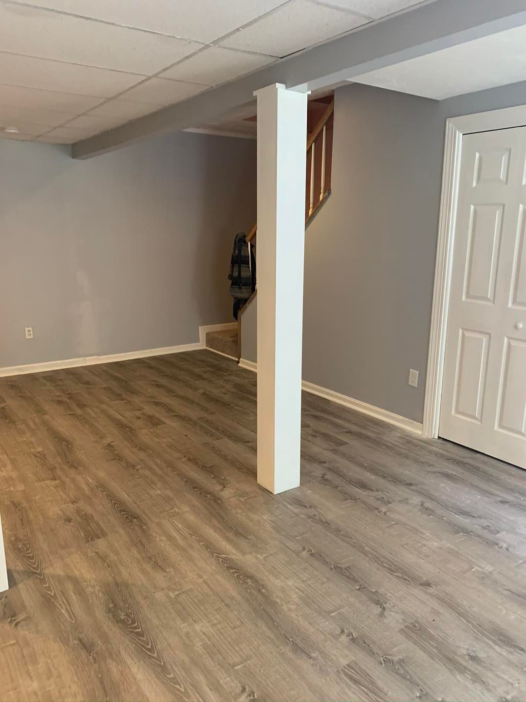 An empty basement with hardwood floors and a staircase