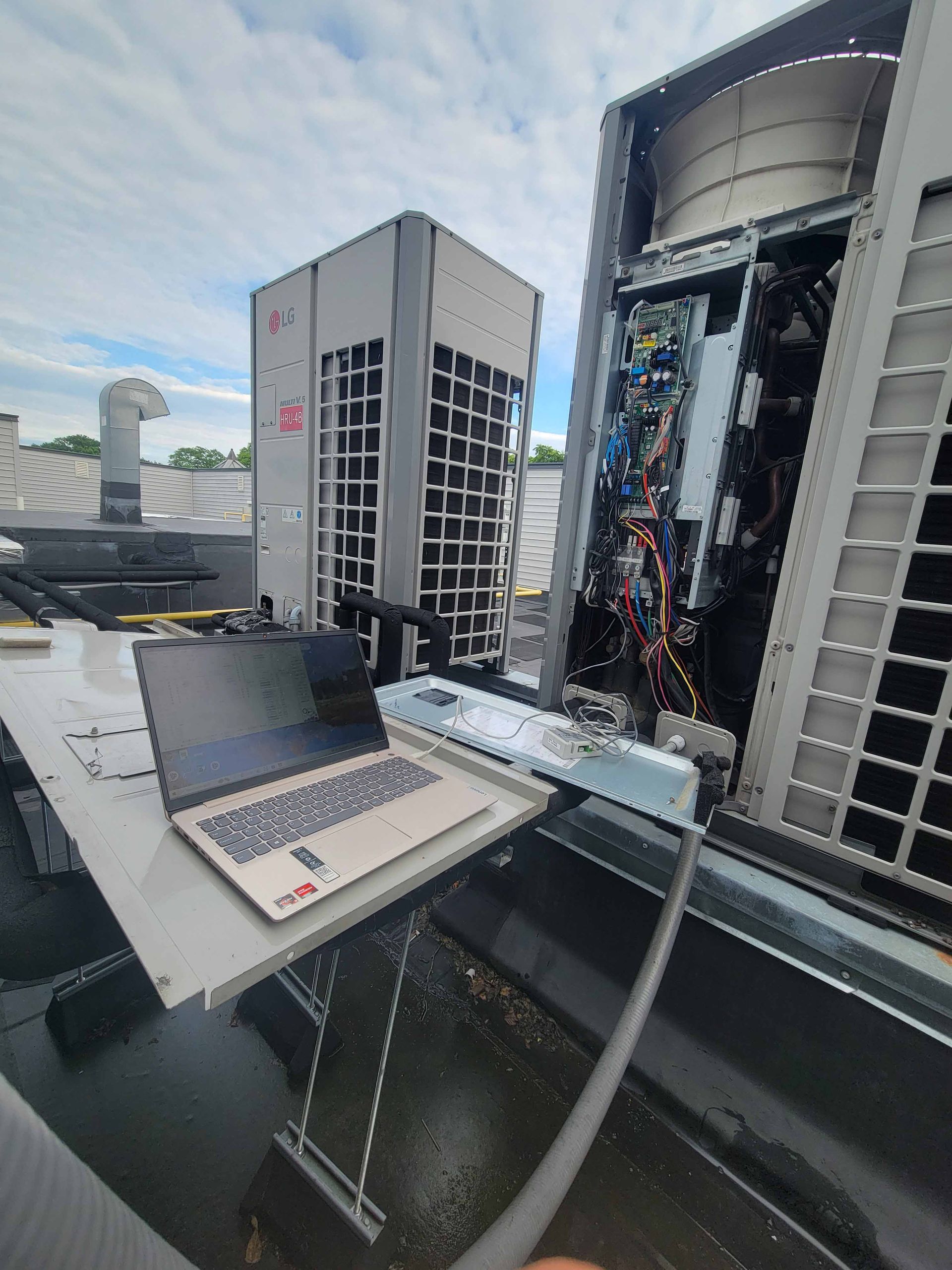 A laptop is sitting on a table next to a large air conditioner.