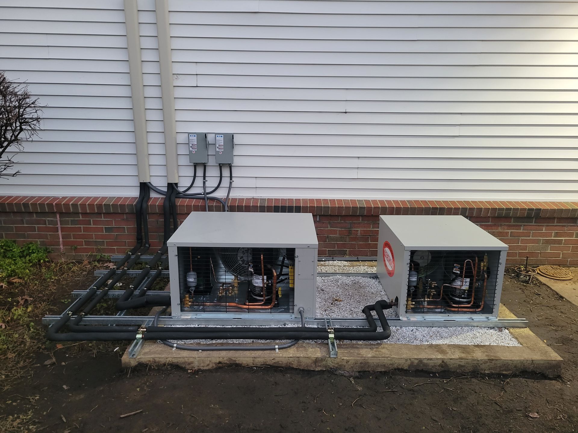 Two air conditioners are sitting outside of a building.