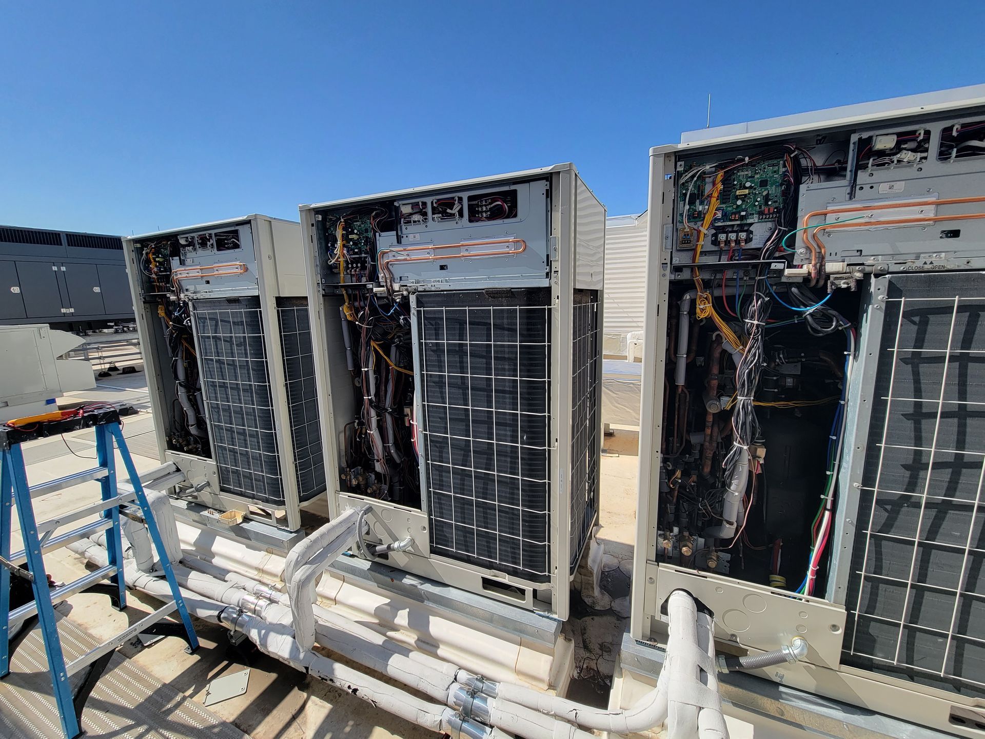 A row of air conditioners are sitting on top of a roof.