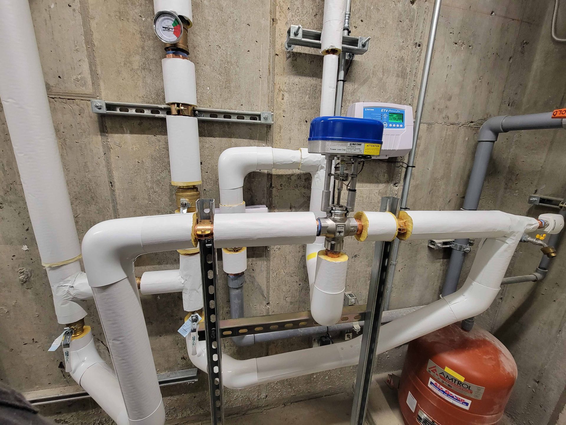 A room filled with lots of pipes and a red tank.