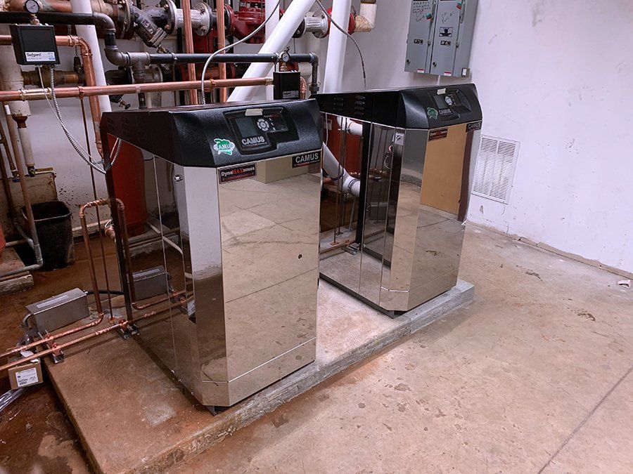 Two stainless steel boilers are sitting next to each other in a room.