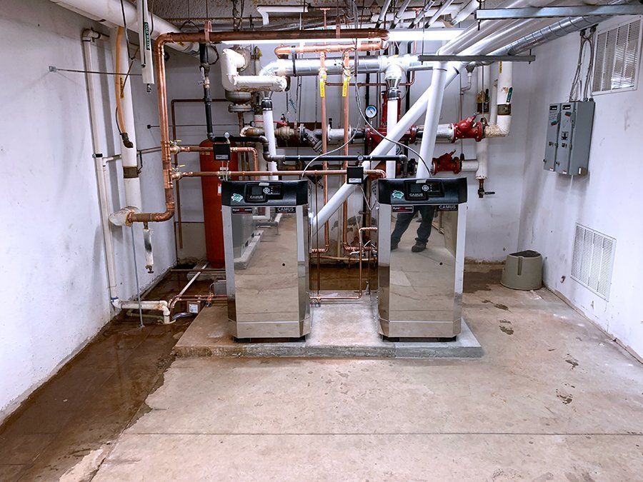 A room with two boilers and pipes in it