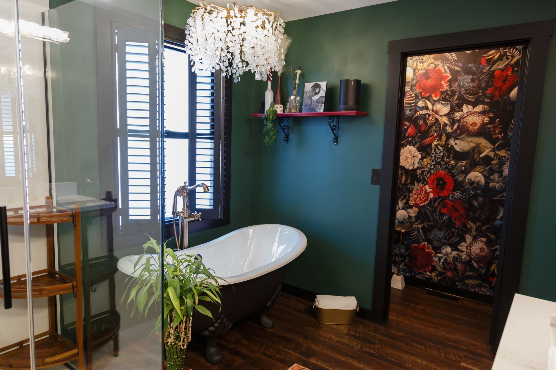 Bathroom with dark green walls, a white tub, floral wallpaper doorway, and a chandelier.