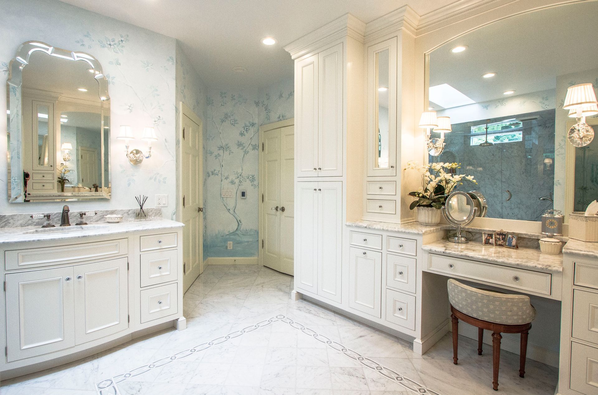Elegant white bathroom with marble countertops and a vanity, decorative mirrors, and a light blue wall.