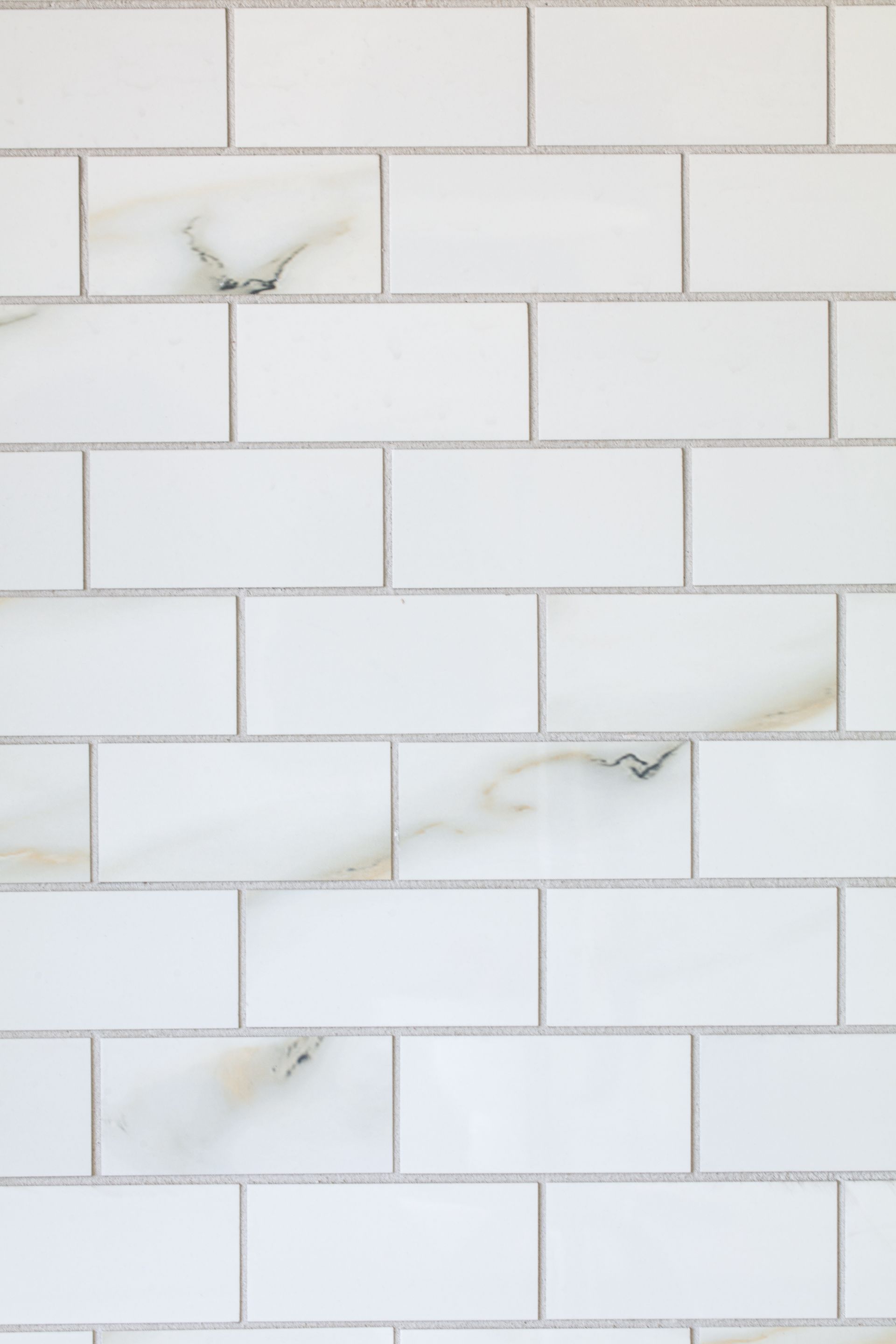 White rectangular subway tiles with subtle veining, arranged in a brick pattern.