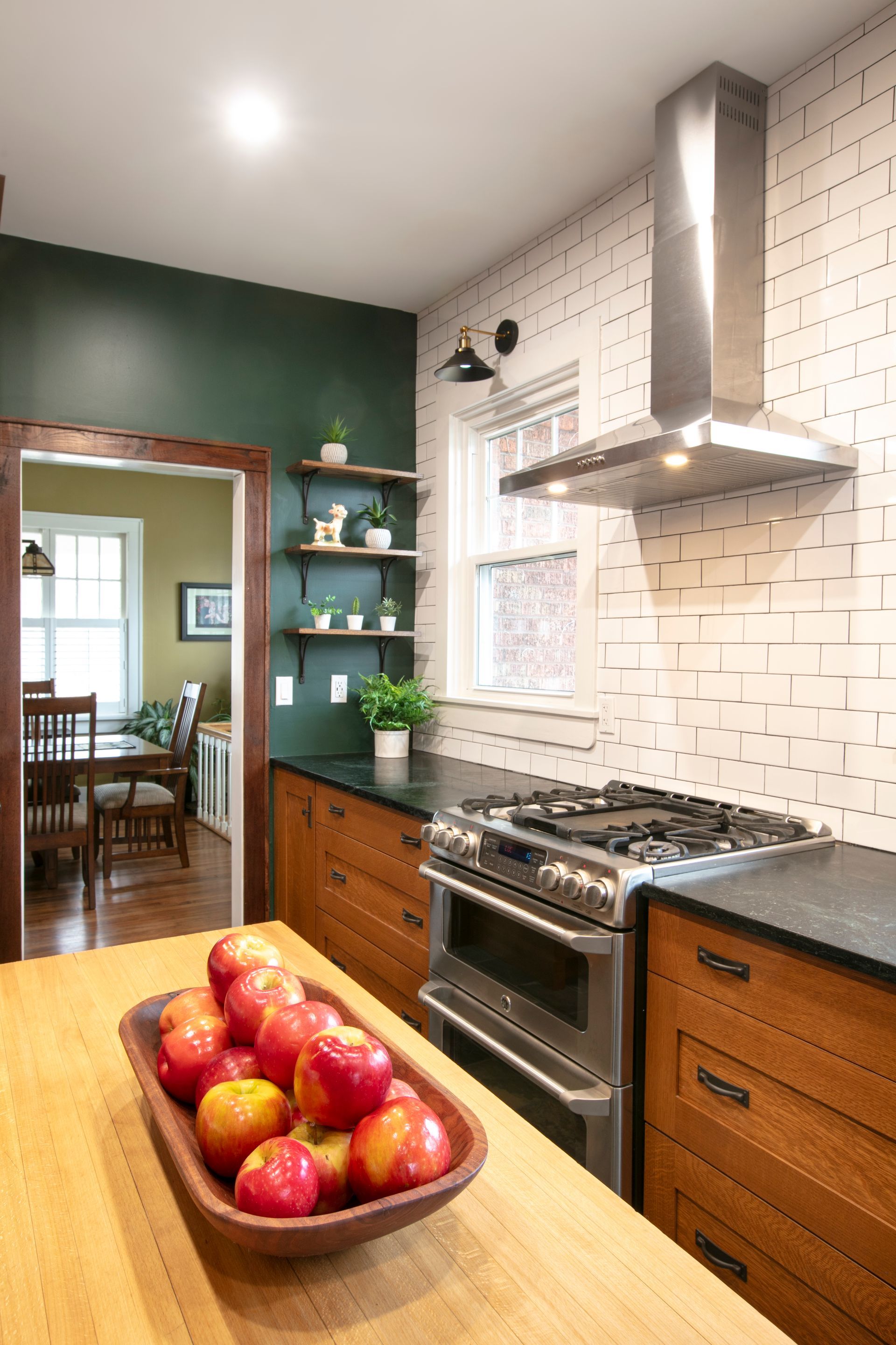 Kitchen with wooden cabinets, brick backsplash, and a bowl of apples on a countertop.