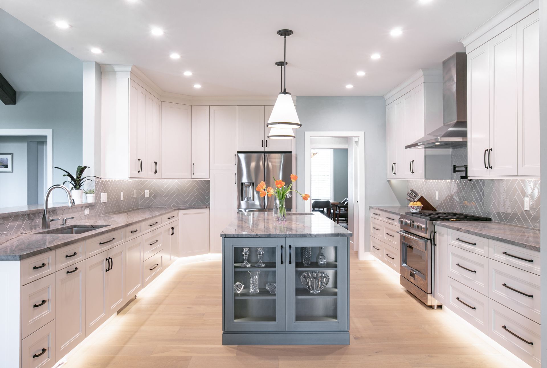 Modern kitchen with white cabinets, gray countertops, and a blue island.