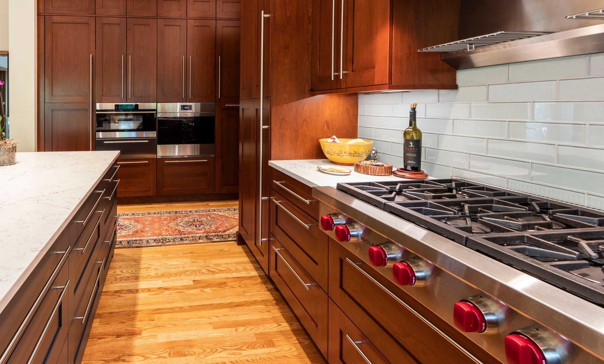 Kitchen with wood cabinets, stainless steel appliances, white countertops, and wood floors.