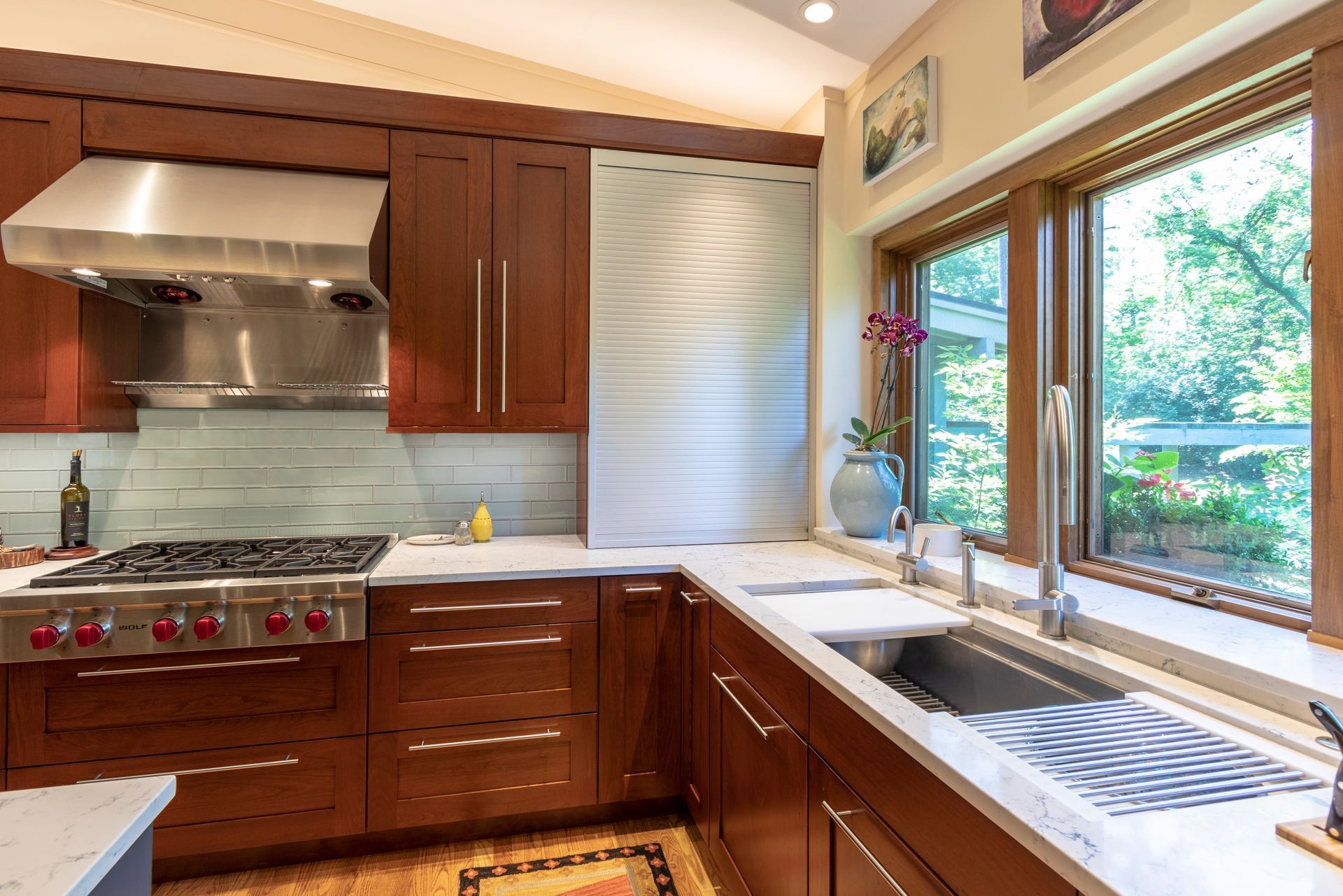 Modern kitchen with dark wood cabinets, stainless steel appliances, and a window overlooking greenery.