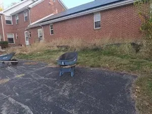 Two wheelbarrows are parked in front of a brick house.
