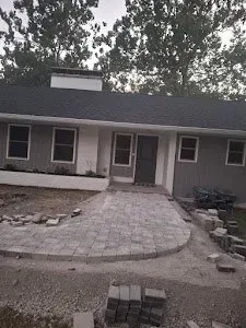 A house with a brick walkway leading to it is being built.