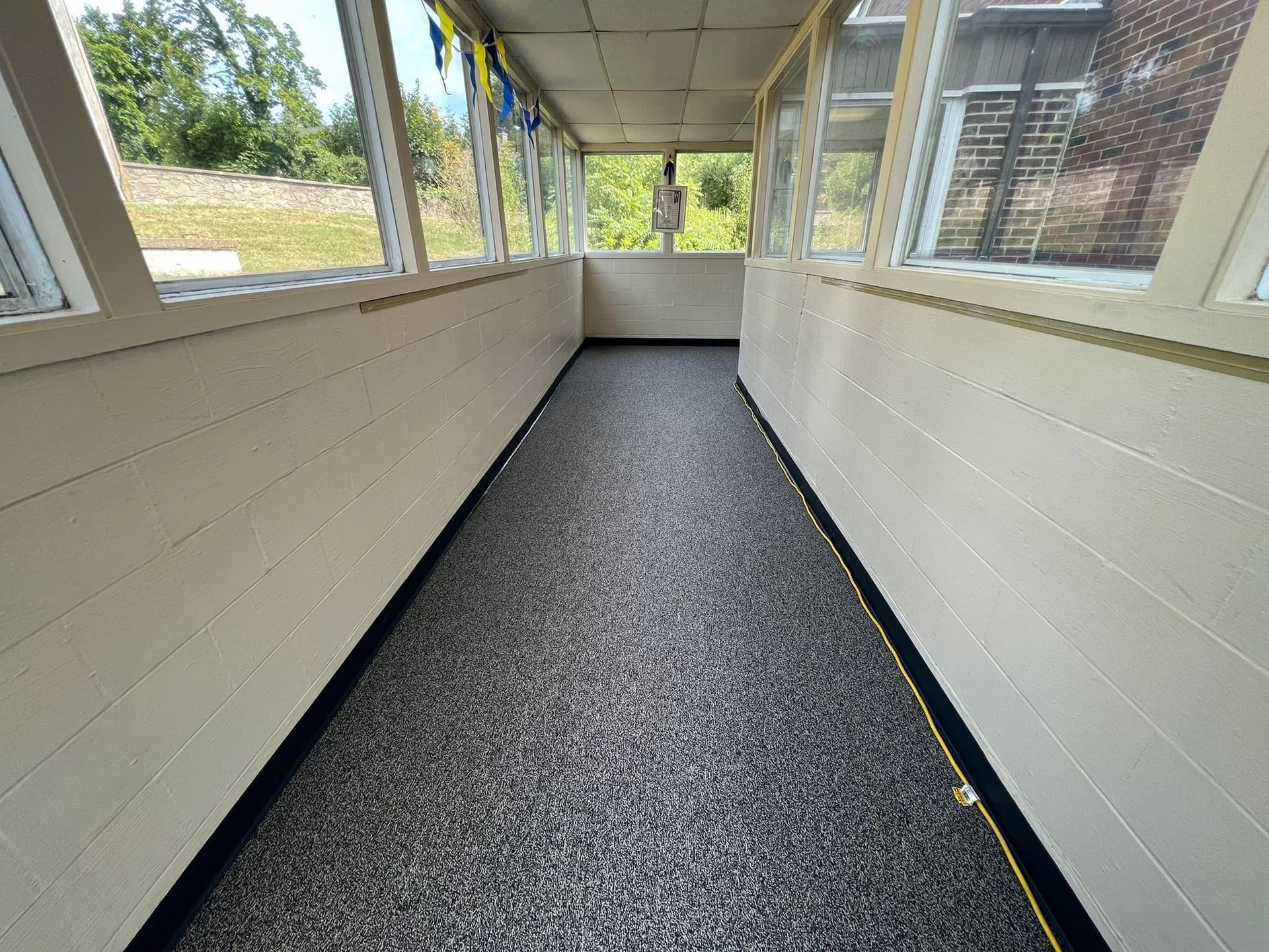 Enclosed porch with speckled gray floor, beige walls, and windows.