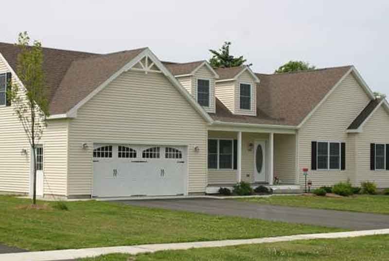 A white house with a brown roof and a white garage door