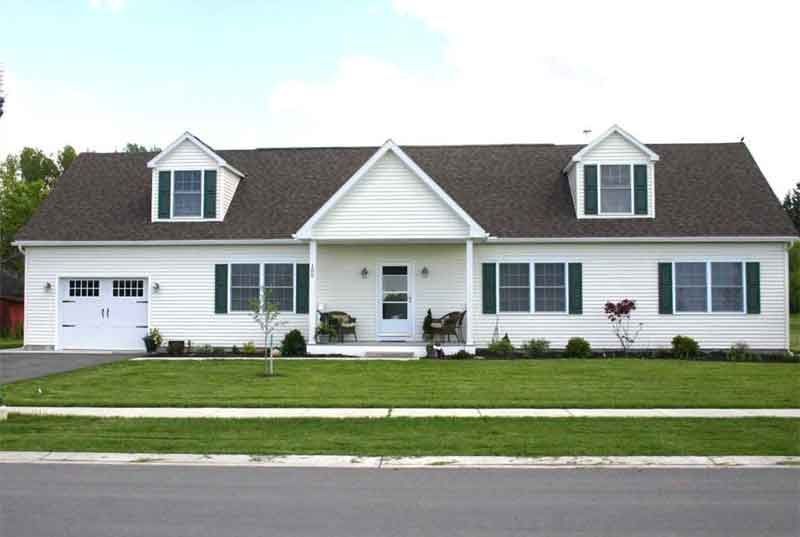 A white house with a brown roof and green shutters
