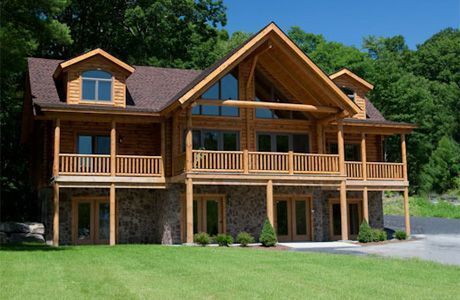 A large log cabin is sitting on top of a lush green hillside surrounded by trees.