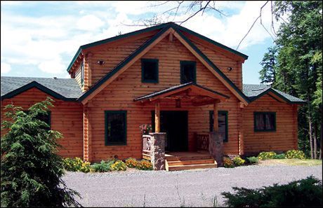 A large wooden house with a driveway leading to it