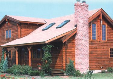 A large wooden house with a brick chimney and skylights on the roof