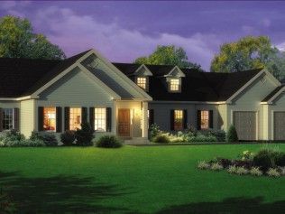 A large white house with black shutters is lit up at night