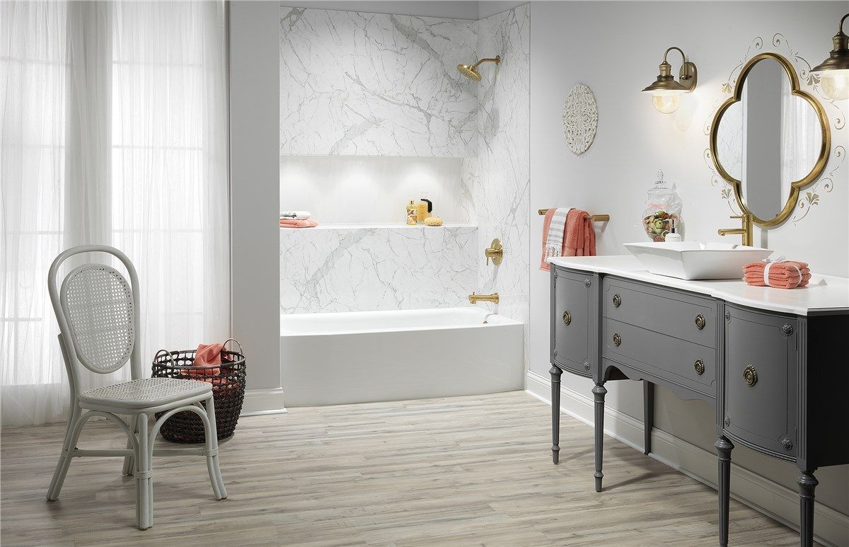 Elegant bathroom with marble accents, gold fixtures, antique vanity, and a white chair.