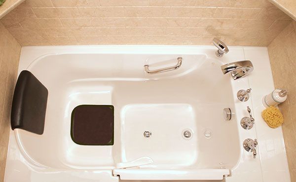 White walk-in bathtub with a seat, grab bars, and faucet fixtures, likely designed for accessibility.