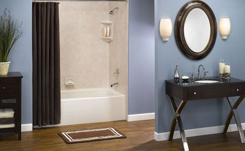 Bathroom with shower/tub combo, dark brown shower curtain, blue walls, dark vanity with oval mirror, and wooden floor.