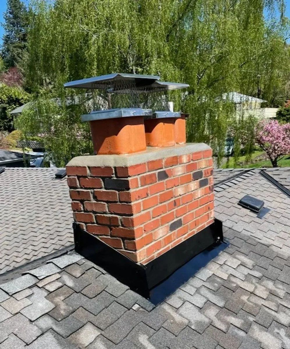 Brick chimney with metal cap on a gray shingle roof