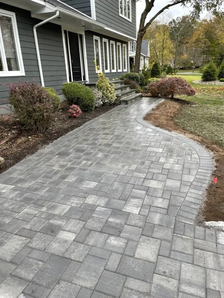 Curved gray stone walkway beside a dark gray house