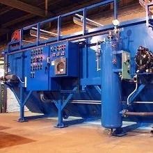 Blue industrial machine with control panels and piping in a factory setting.