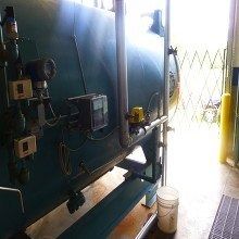 Large industrial tank with gauges, pipes, and a door, likely in a factory or plant.