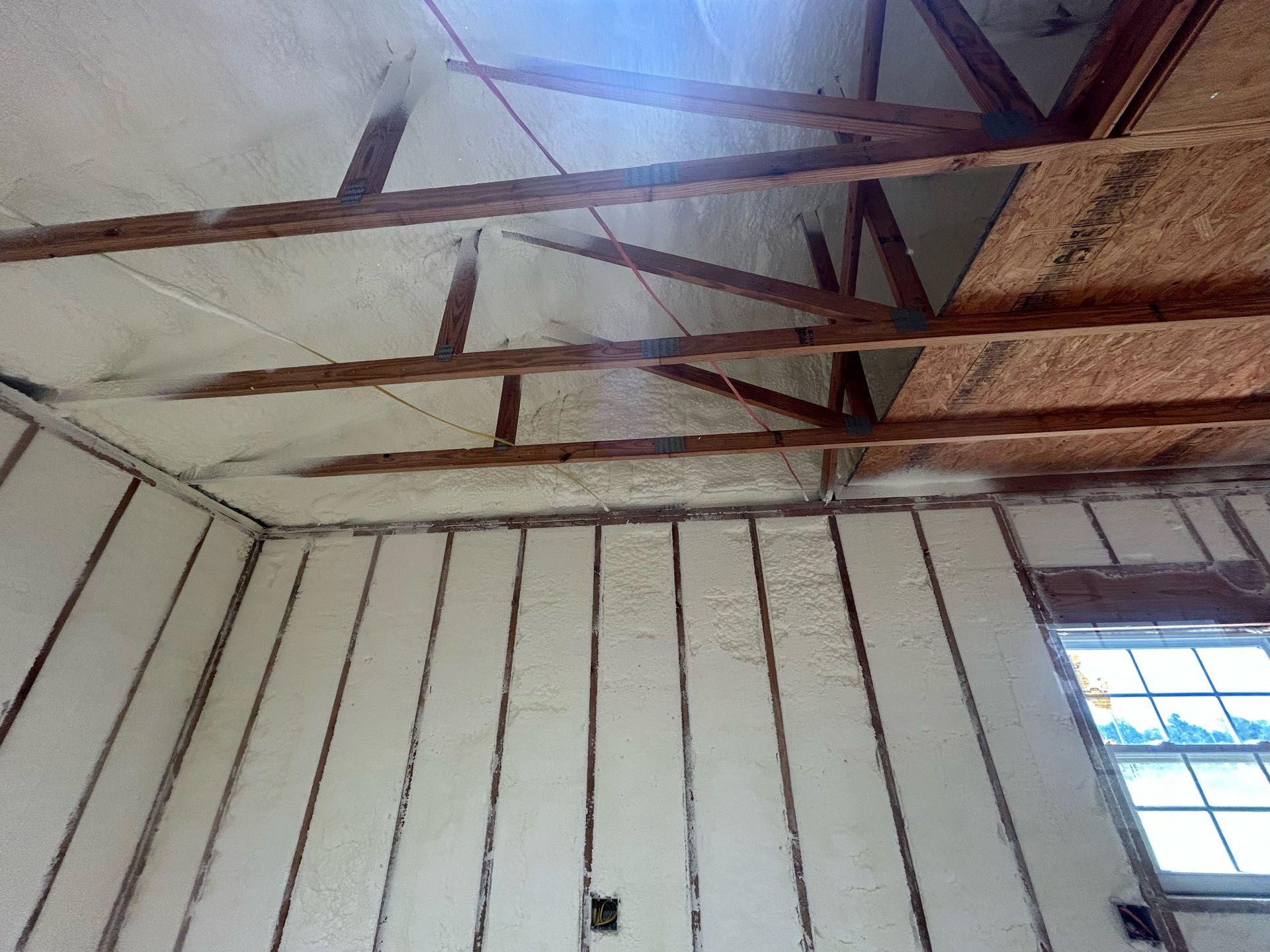 The ceiling of a room with a window and wooden beams.