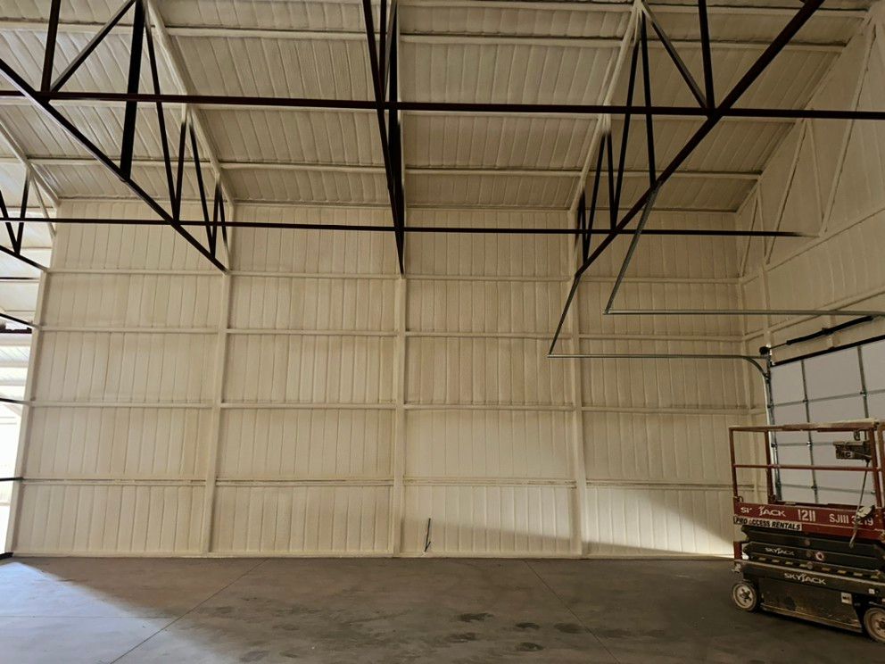 An empty warehouse with a scissor lift in the middle of it.