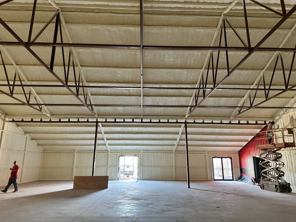 A man is walking through a large empty warehouse.