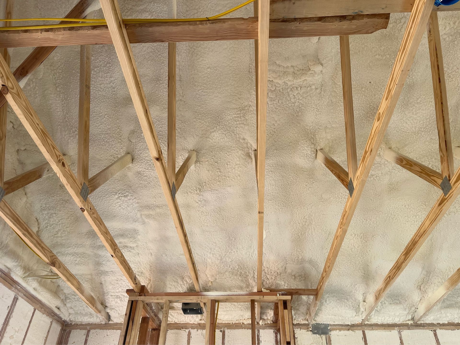 A ceiling with wooden beams and spray foam on it.