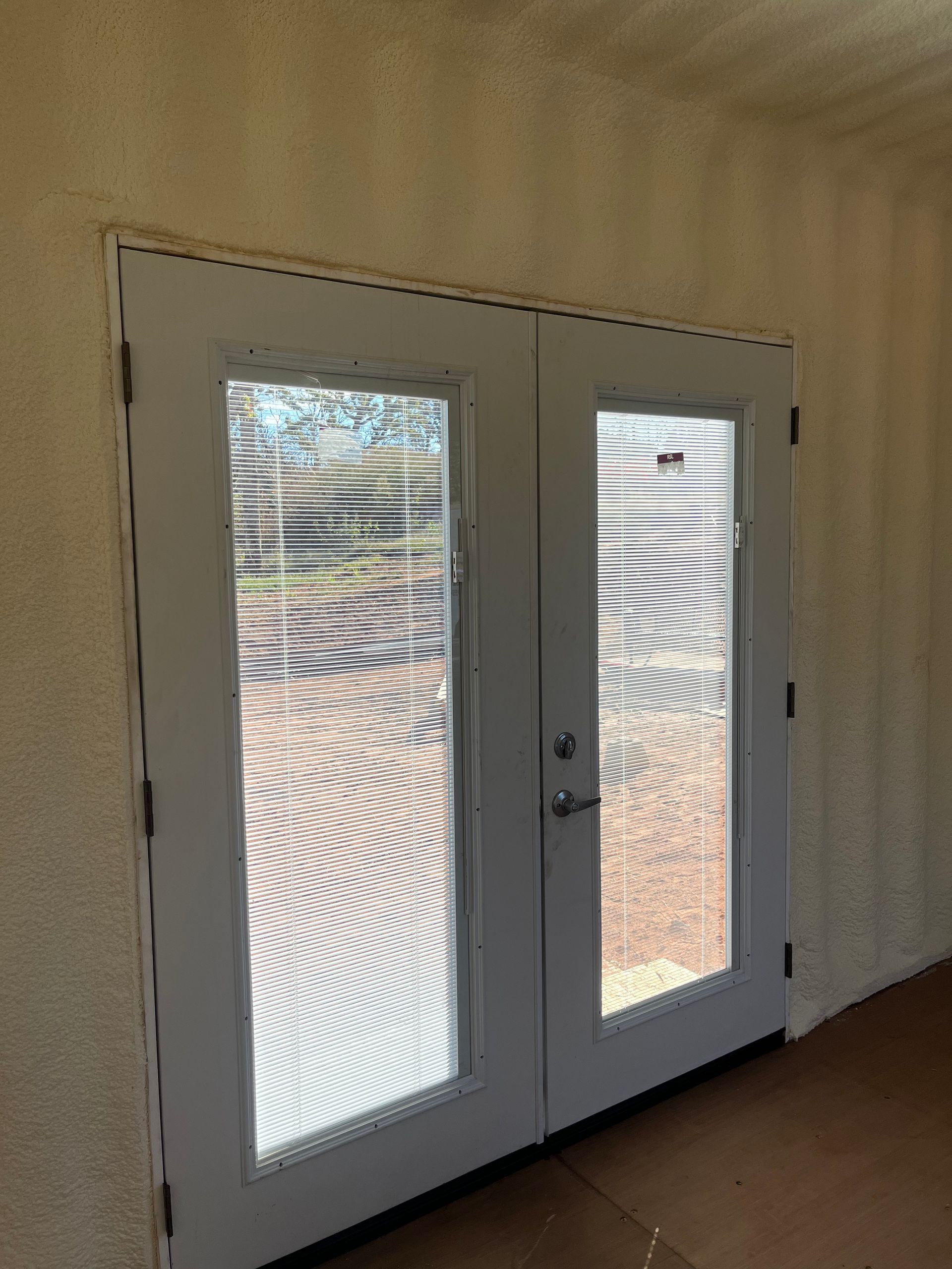 A pair of white french doors with blinds in a room.