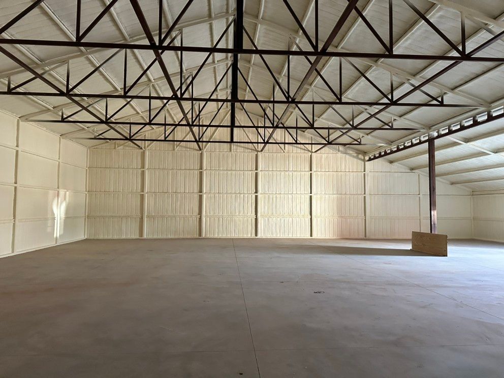 A large empty warehouse with a metal roof and a concrete floor.
