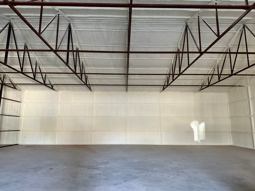 The inside of an empty warehouse with a ceiling and a concrete floor.