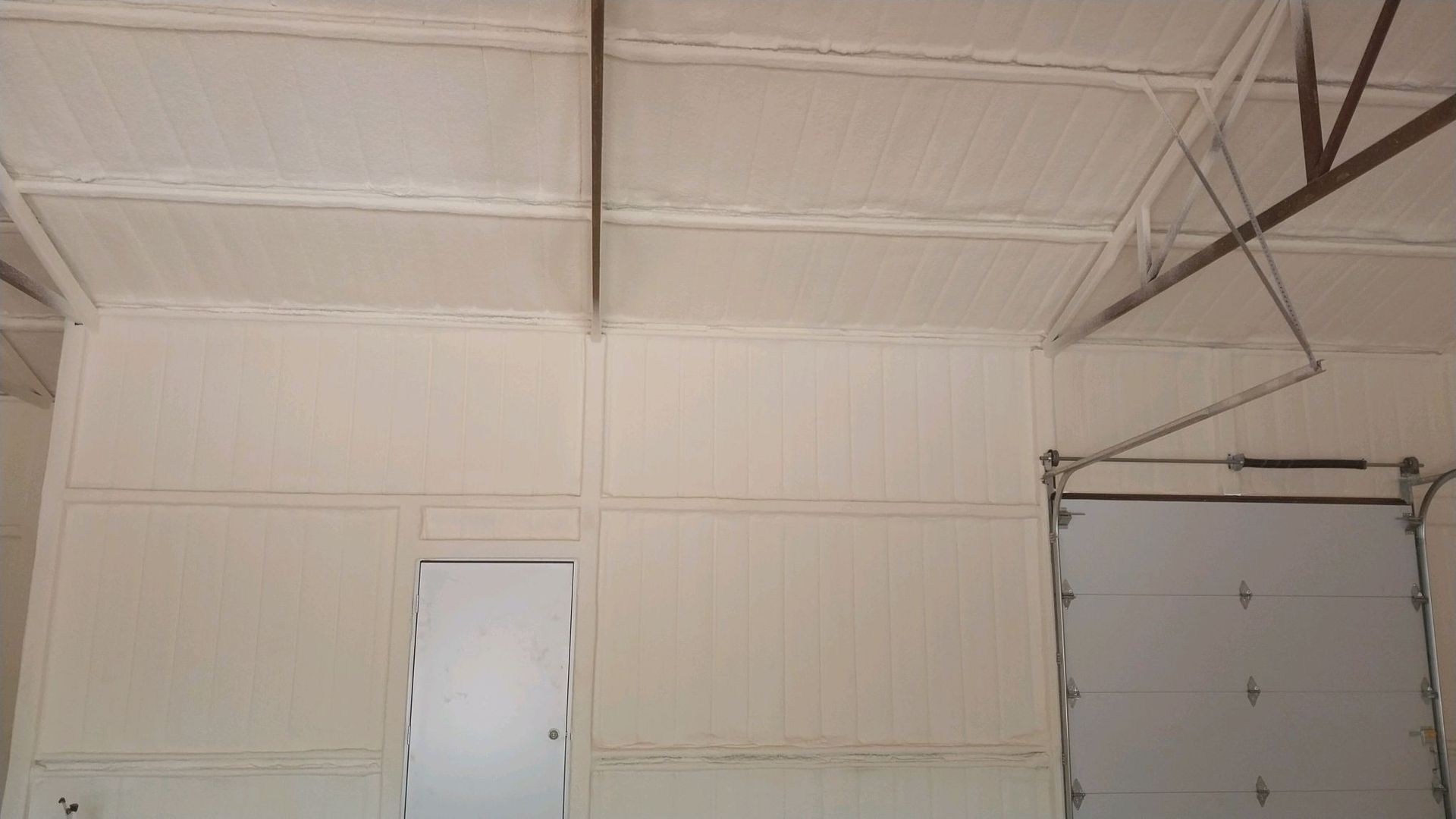 A garage with a door and a ceiling with foam on it.