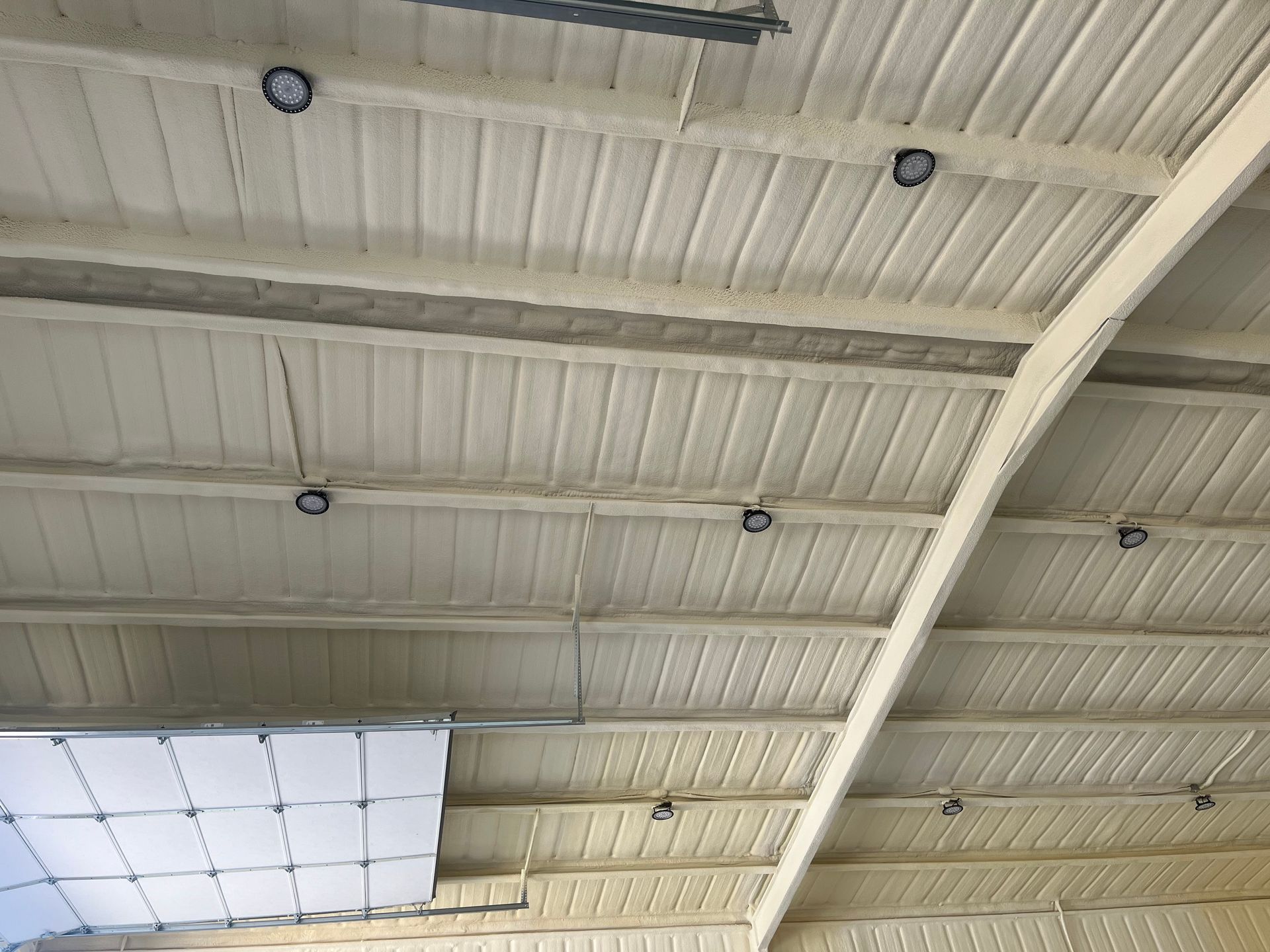 The ceiling of a building is painted white and has a lot of beams.