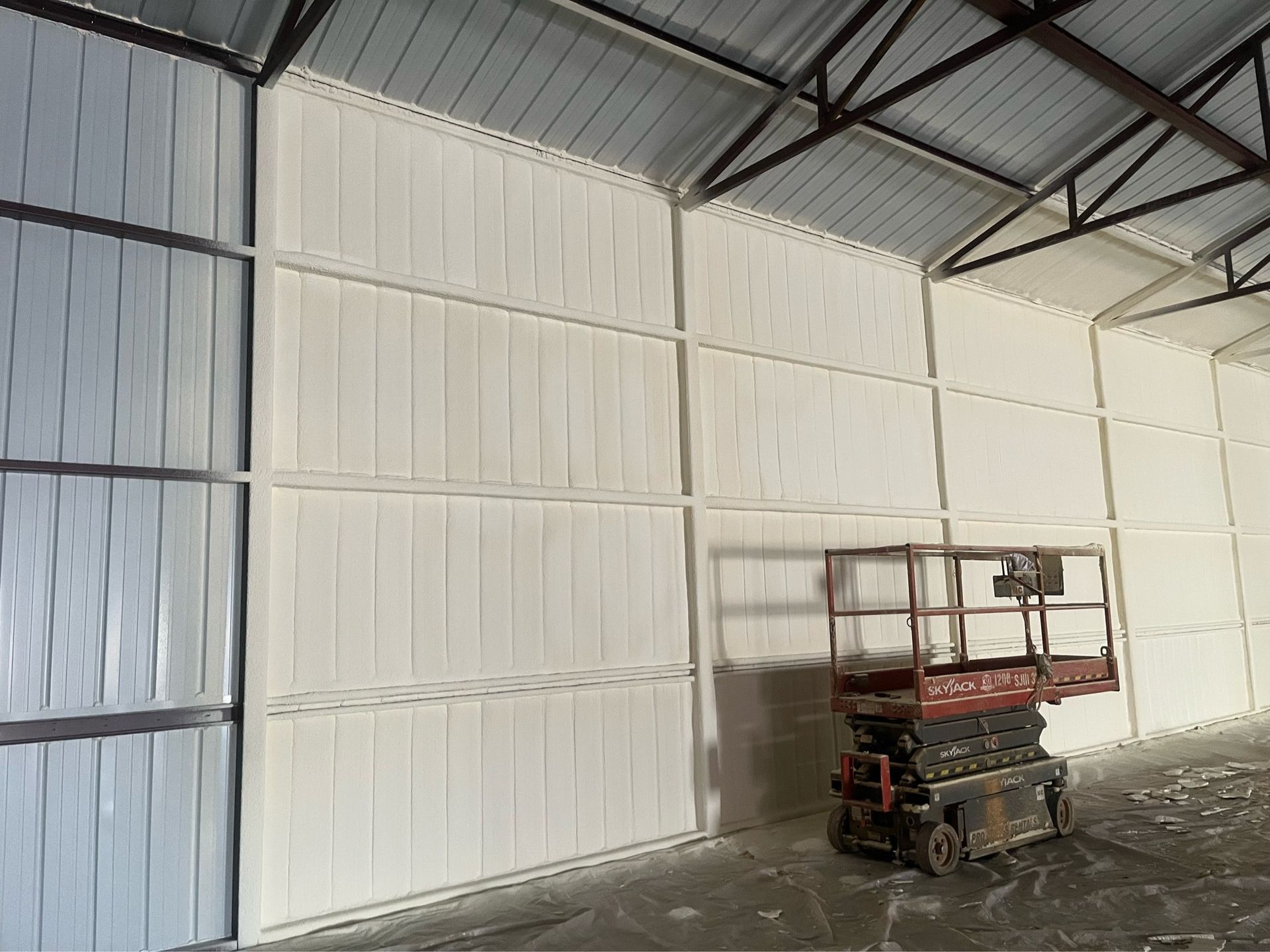 A scissor lift is parked in a large warehouse.