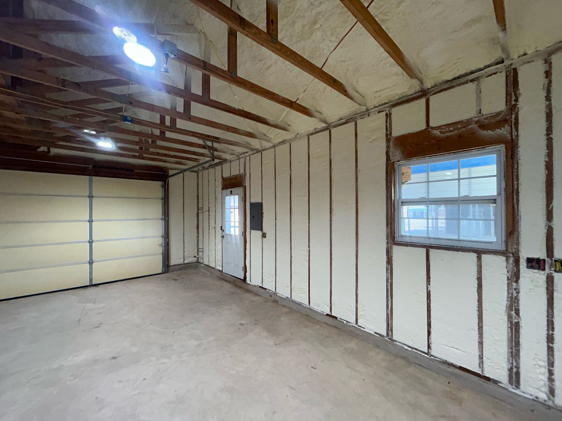 An empty garage with a garage door and a window.