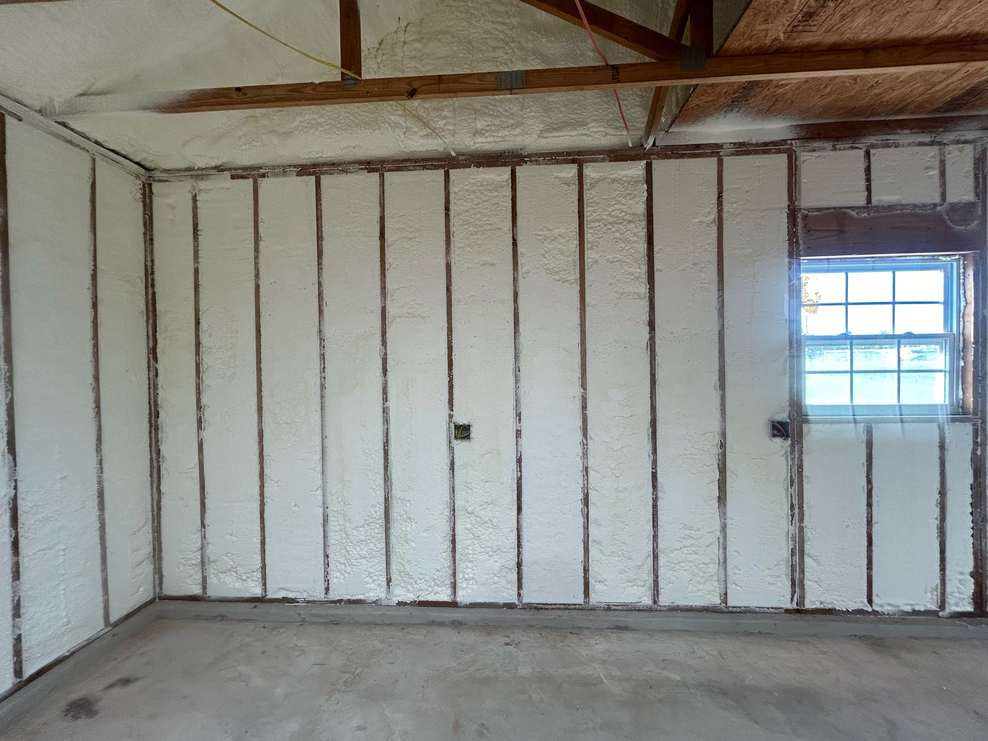 An empty room with foam insulation on the walls and a window.