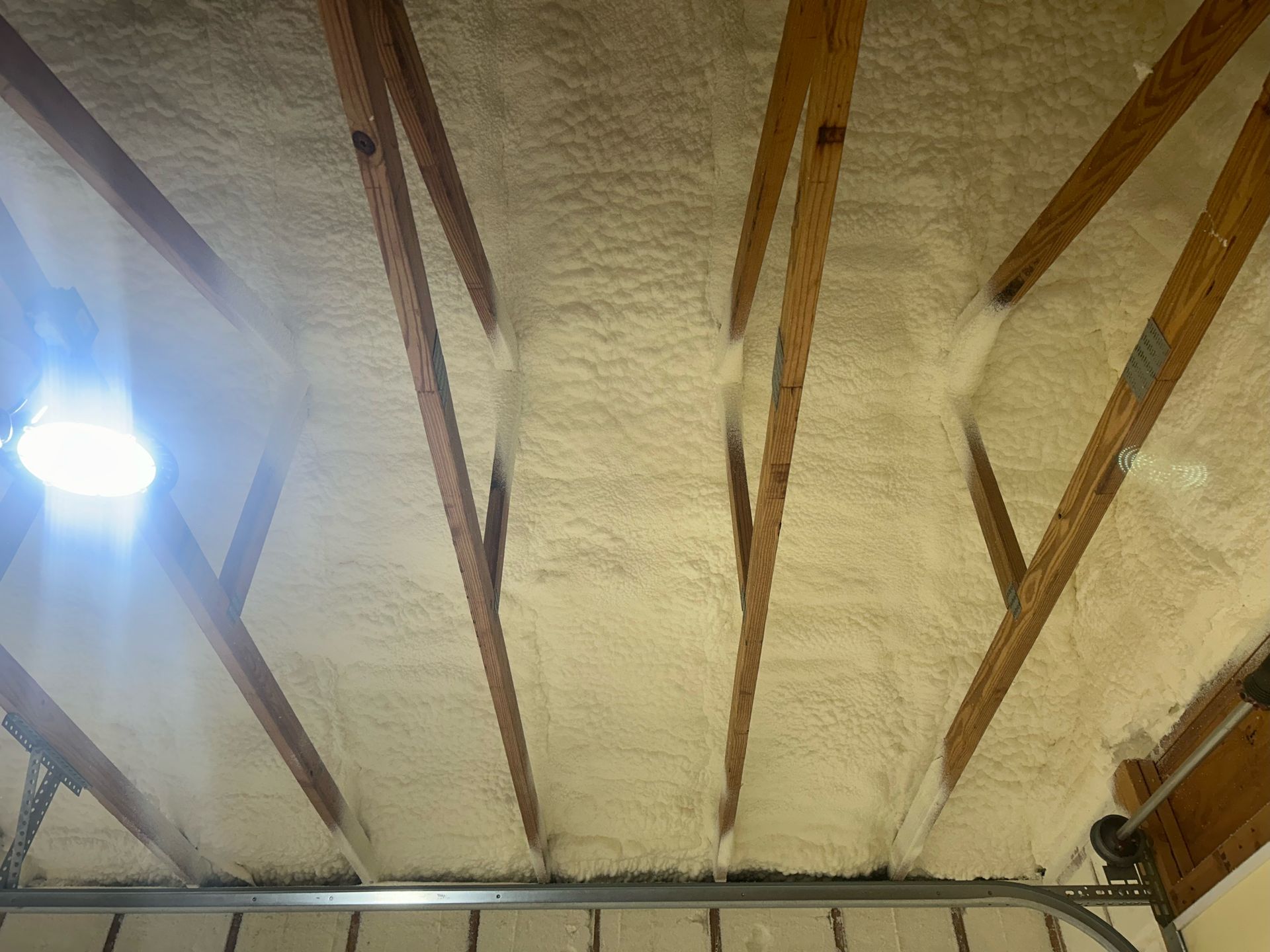 The ceiling of a garage is covered in foam and wooden beams.