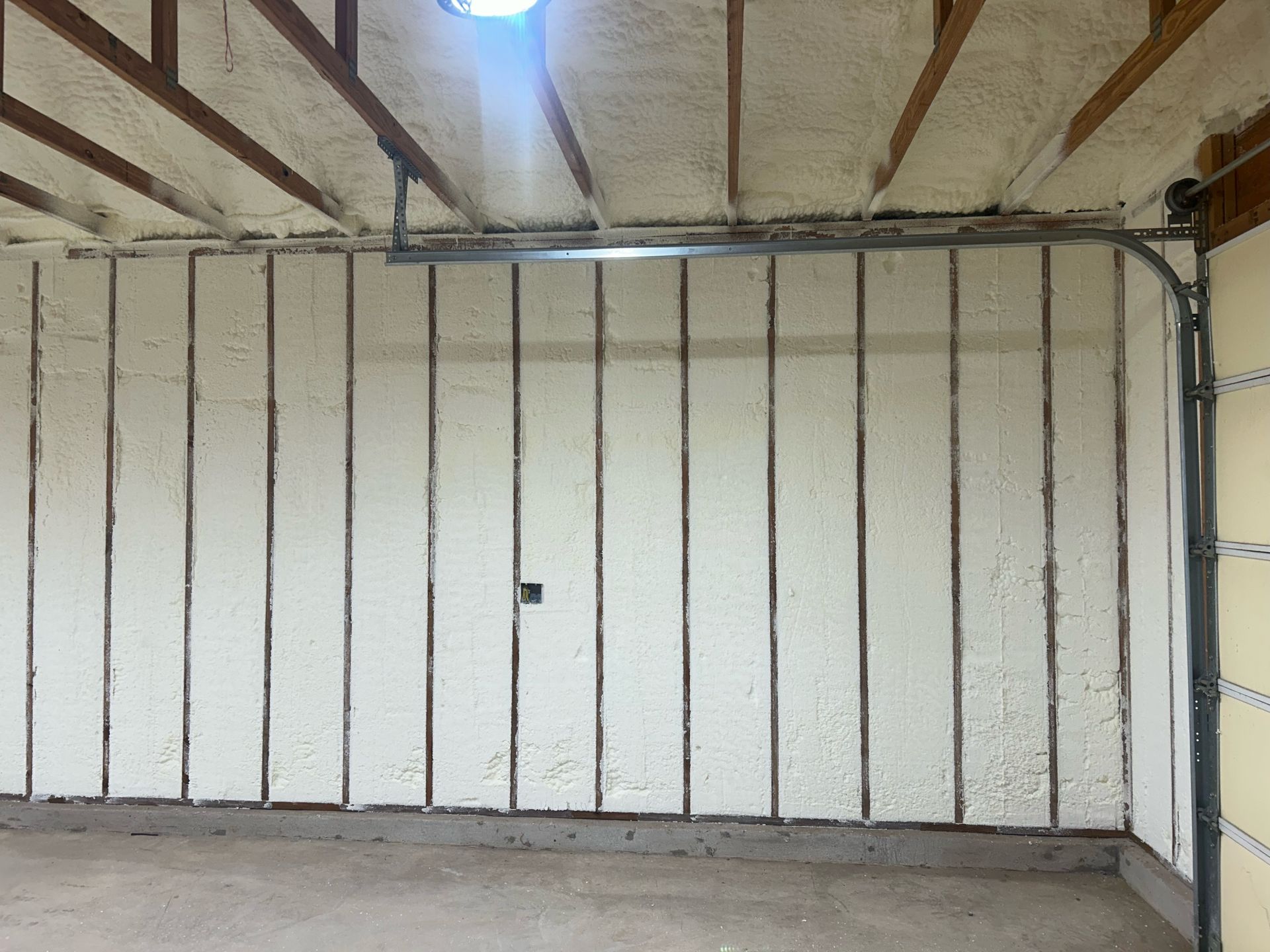 A garage with a garage door and a wall covered in insulation.