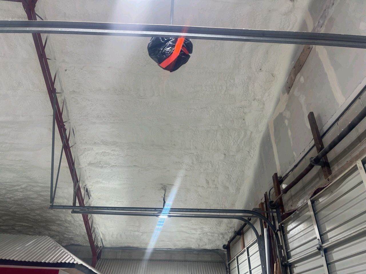 A basketball is hanging from the ceiling of a garage.
